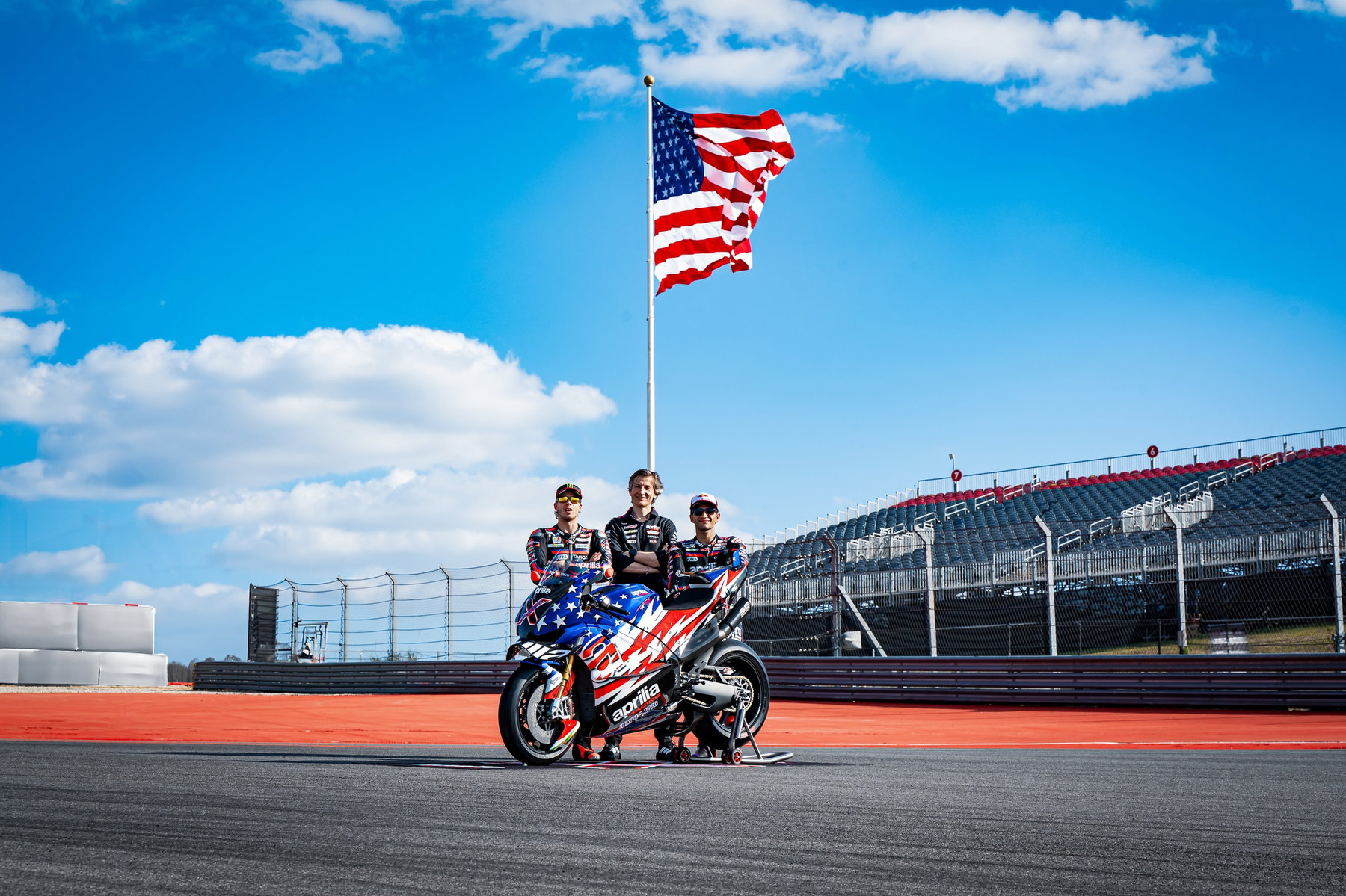 Marco Bezzecchi and Jorge Martin posing with the Aprilia X 250TH under the US flag – unveiling of the Limited Edition at MotoGP Austin 2026
