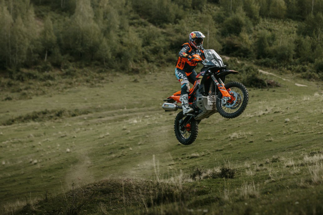 KTM 890 Adventure R Rally 2026 in der Luft ueber Wiese – Seitenansicht Sprung Offroad