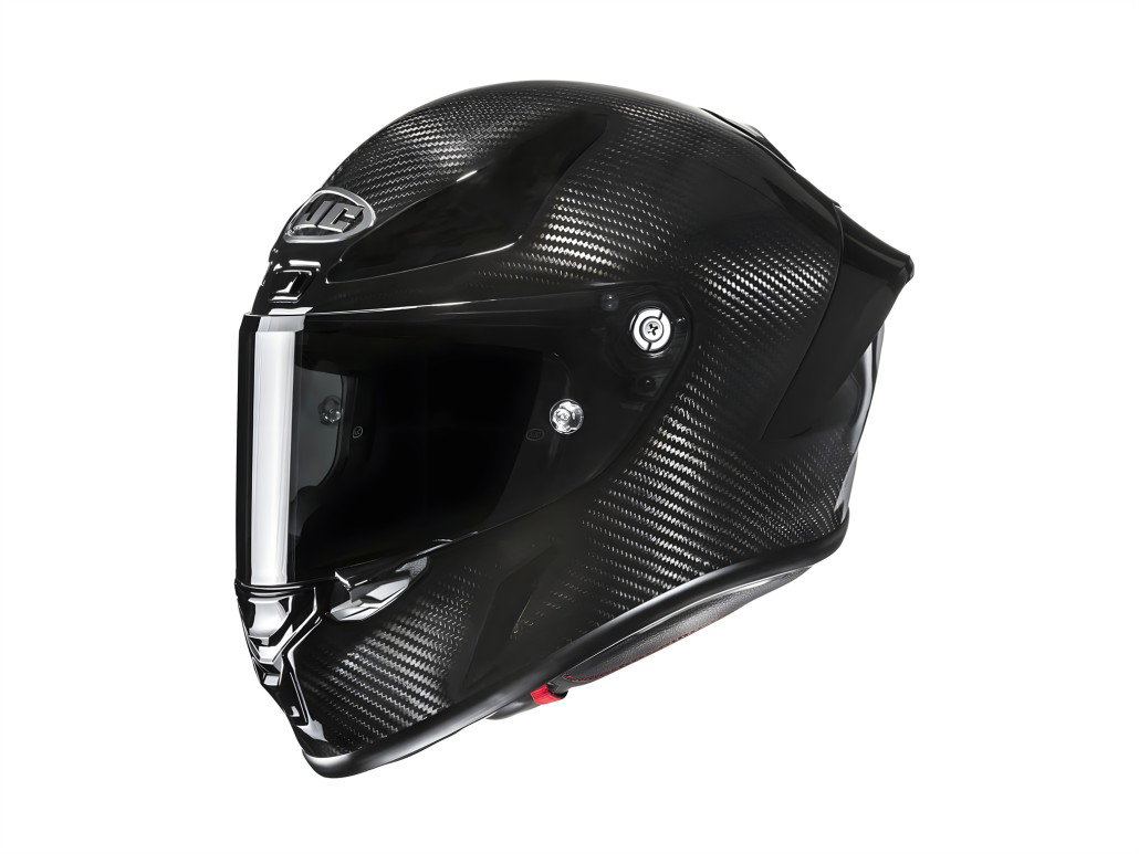HJC RPHA 1 V2 Carbon: Der MotoGP-Helm für ambitionierte Sportfahrer HJC RPHA 1 V2 Carbon 2026 – Dreiviertelansicht von vorn links, dunkles Visier, Metallvisierverschluss, sichtbare Carbon-Faser-Struktur, weißer Hintergrund