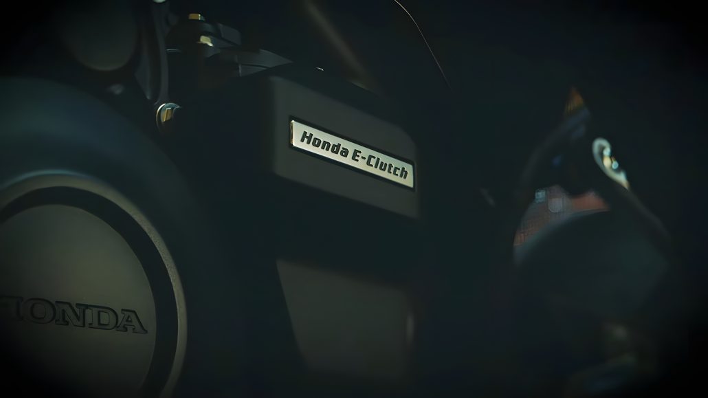 Honda CB400 Super Four und CBR400R Four: Japans 400er-Vierzylinder kehrt zurück 2 Honda E-Clutch – Nahaufnahme des E-Clutch-Schriftzugs am Vierzylinder-Motor mit Honda-Generatordeckel, dunkle Studiobeleuchtung