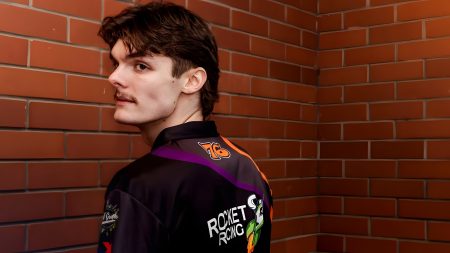 Rhys Stephenson 2026 – Rückansicht in farbiger Rocket Racing Teamjacke mit Orange-Lila-Design vor roter Backsteinwand