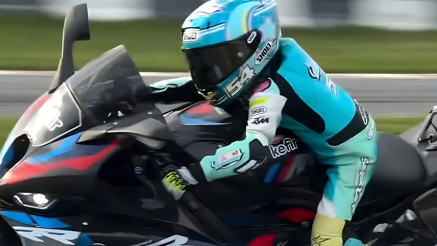 Zayn Sofuoglu auf der BMW M 1000 RR – Nahaufnahme auf der Rennstrecke in türkisfarbenem Lederkombi und Shoei-Helm mit Startnummer 54