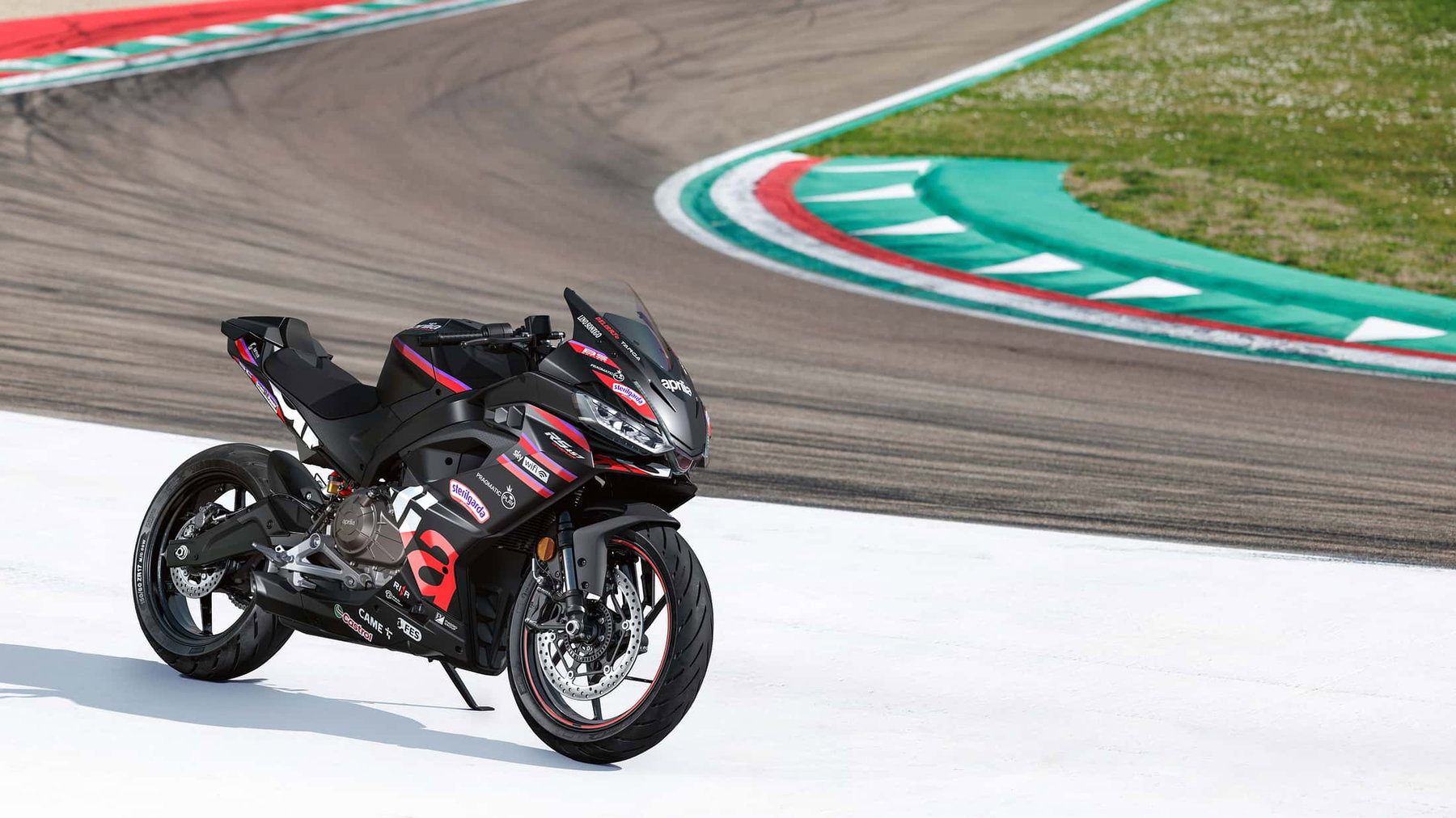 Aprilia RS 457 GP Replica: MotoGP-Flair für die A2-Klasse 2 Aprilia RS 457 GP Replica 2026 – Seitenansicht auf Rennstrecke mit Aprilia-MotoGP-Teamfarben und Curbs im Hintergrund