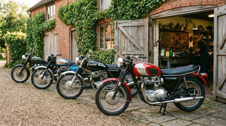 Klassische britische Motorräder aus den 1960er und 1970er Jahren vor einer traditionellen englischen Werkstatt im warmen Morgenlicht