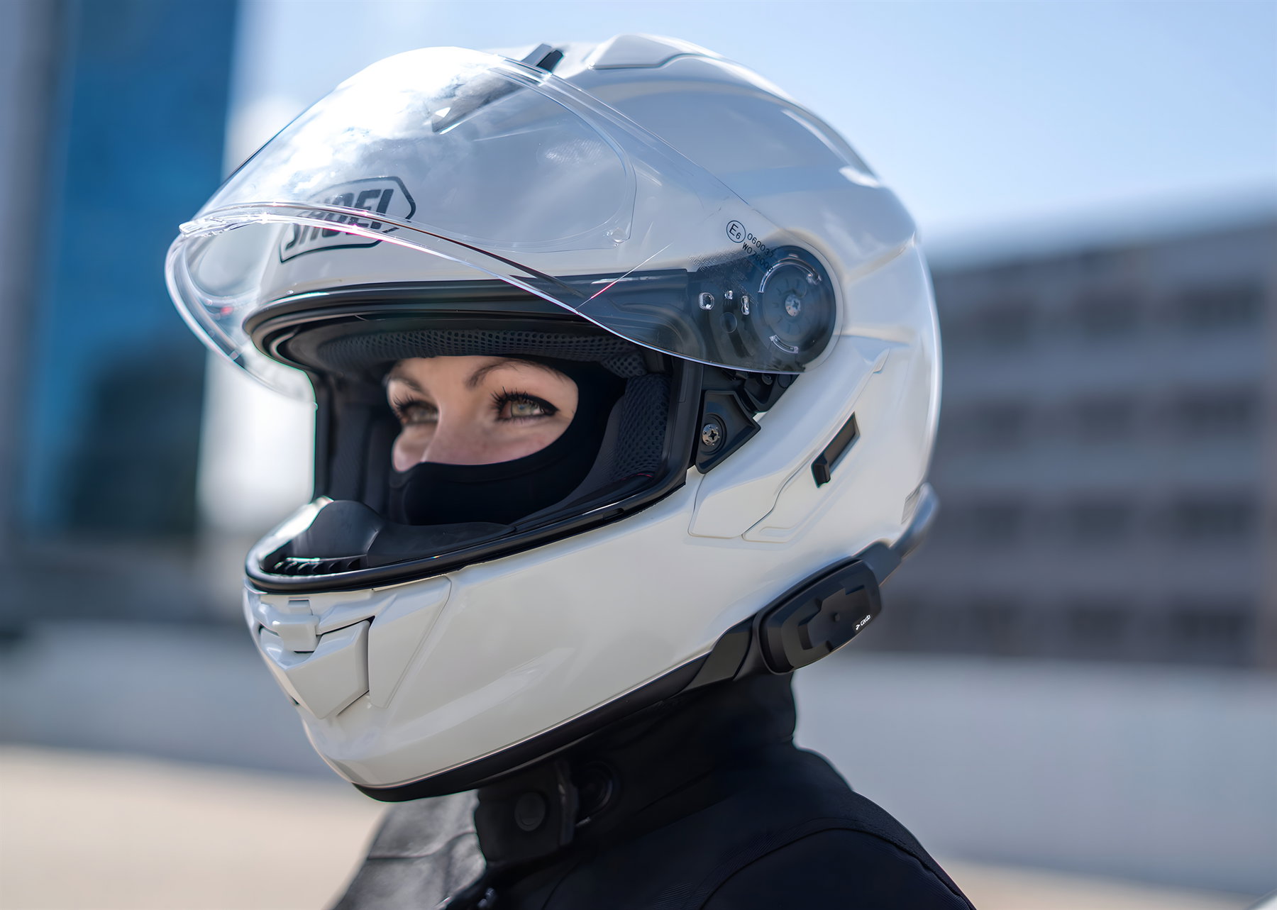Cardo Packtalk-S for Shoei – front view on the white Shoei GT-Air 3 with the visor open, female rider in an urban setting