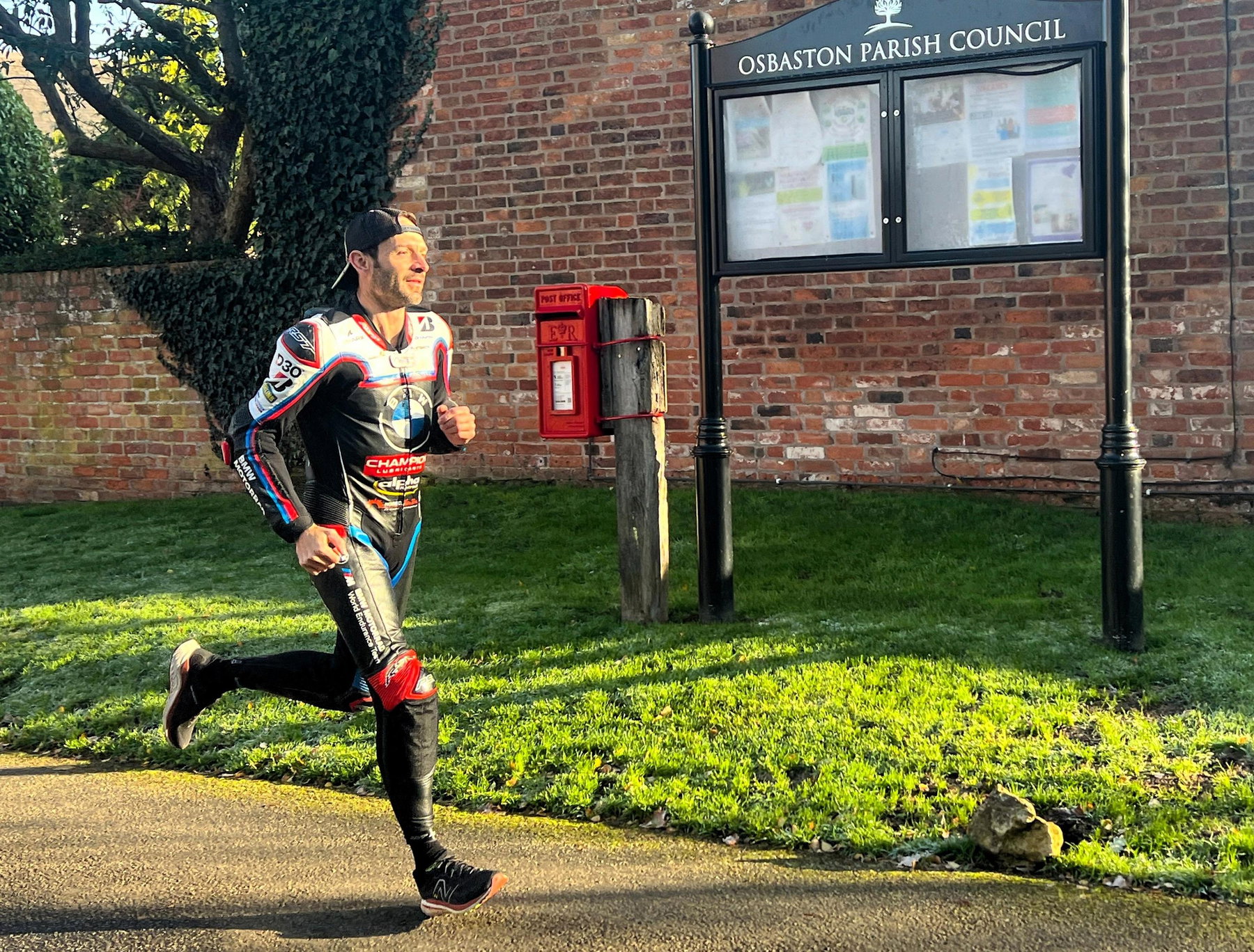 Sylvain Guintoli running in BMW RST racing leather suit with baseball cap through an English village in autumn light as training for the London Marathon