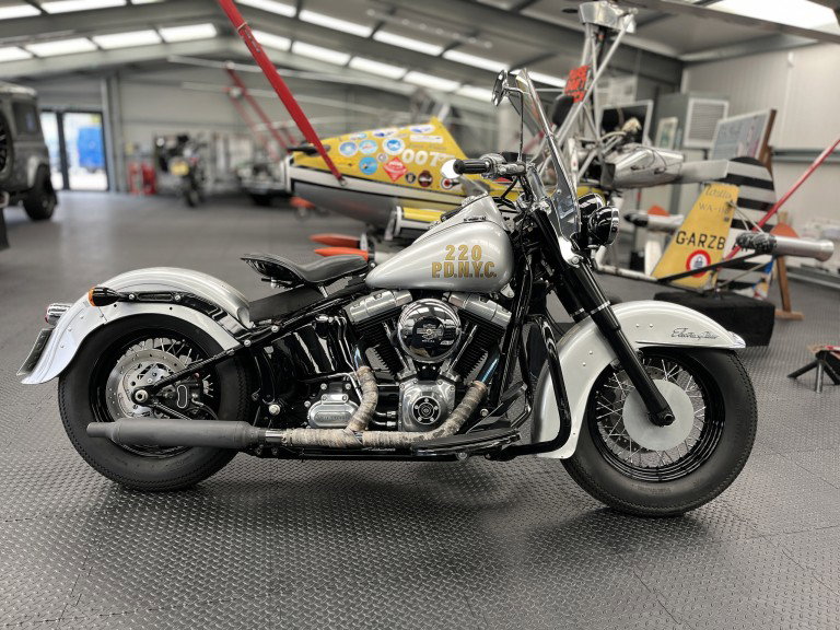 Harley-Davidson Softail Slim aus Indiana Jones kommt unter den Hammer Harley-Davidson Softail Slim 2016 Indiana Jones – Seitenansicht im NYPD-Polizei-Design mit goldener 220 P.D.N.Y.C. Beschriftung in Flugzeug-Hangar