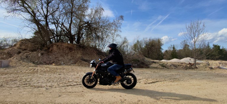 HoverAir X1 ProMax: Autonome Mini-Drohne im Motorrad-Test Motorradfahrer in Seitenansicht auf Schotterflaeche aufgenommen mit der HoverAir X1 ProMax