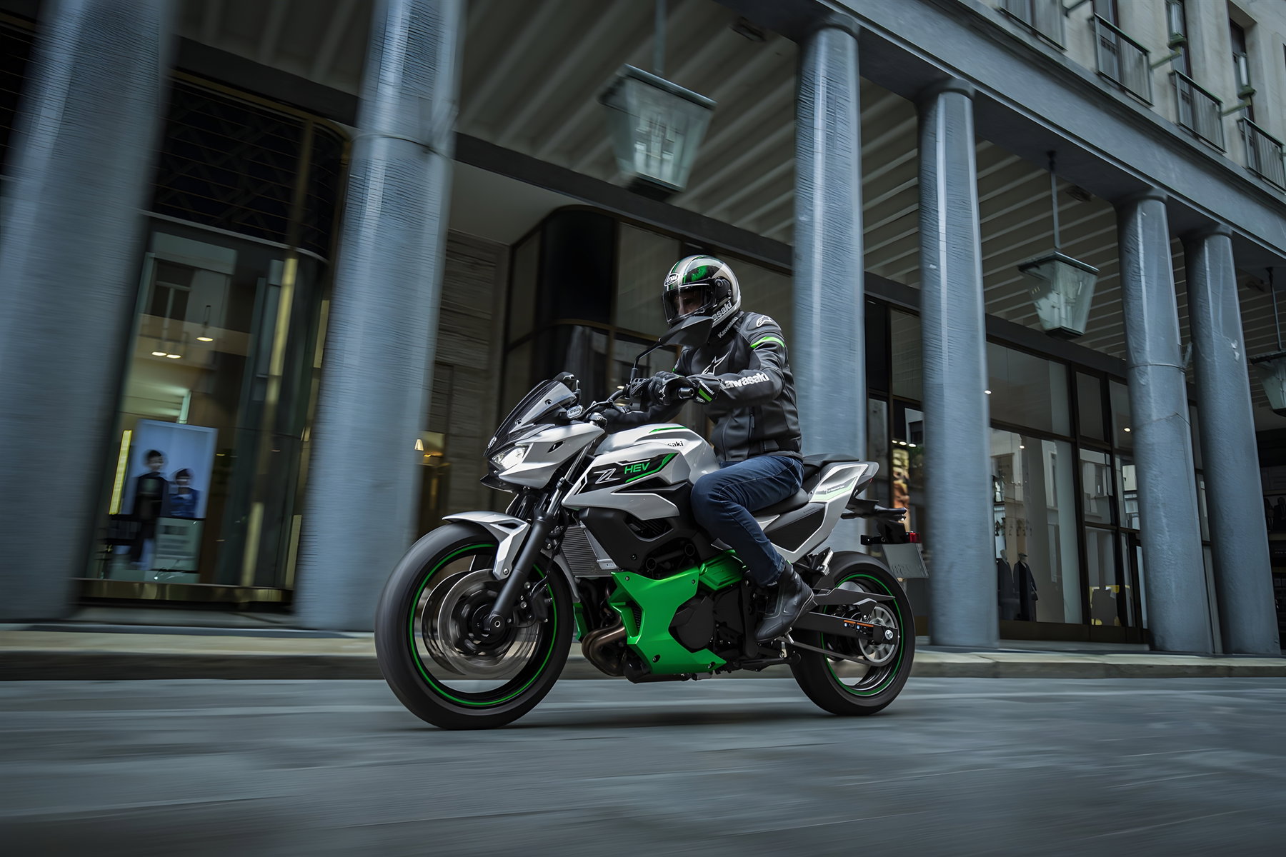 Kawasaki Ninja 7 Hybrid und Z7 Hybrid: Software-Update macht die Hybrid-Motorräder alltagstauglicher 2 Kawasaki Z7 Hybrid SE 2026 – Fahraufnahme in der Stadt mit Fahrer vor Säulengebäude, Silber-Grün-Lackierung