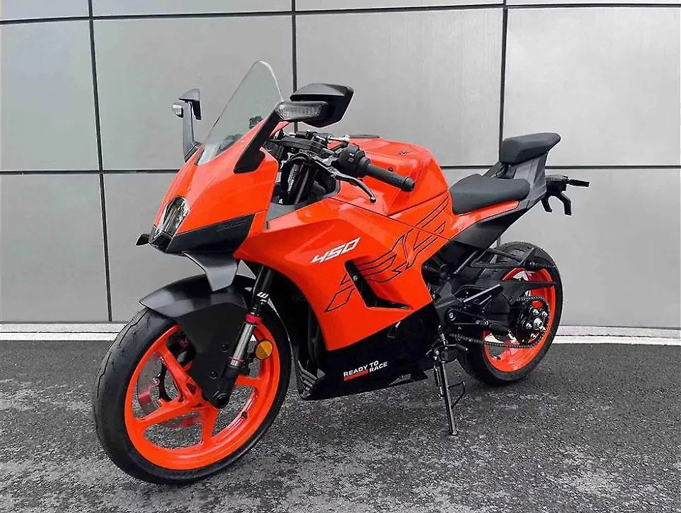 KTM RC 450 2026 – Seitenansicht in Orange mit vollverkleideter Karosserie, orangefarbenen Felgen und Ready-to-Race-Grafik