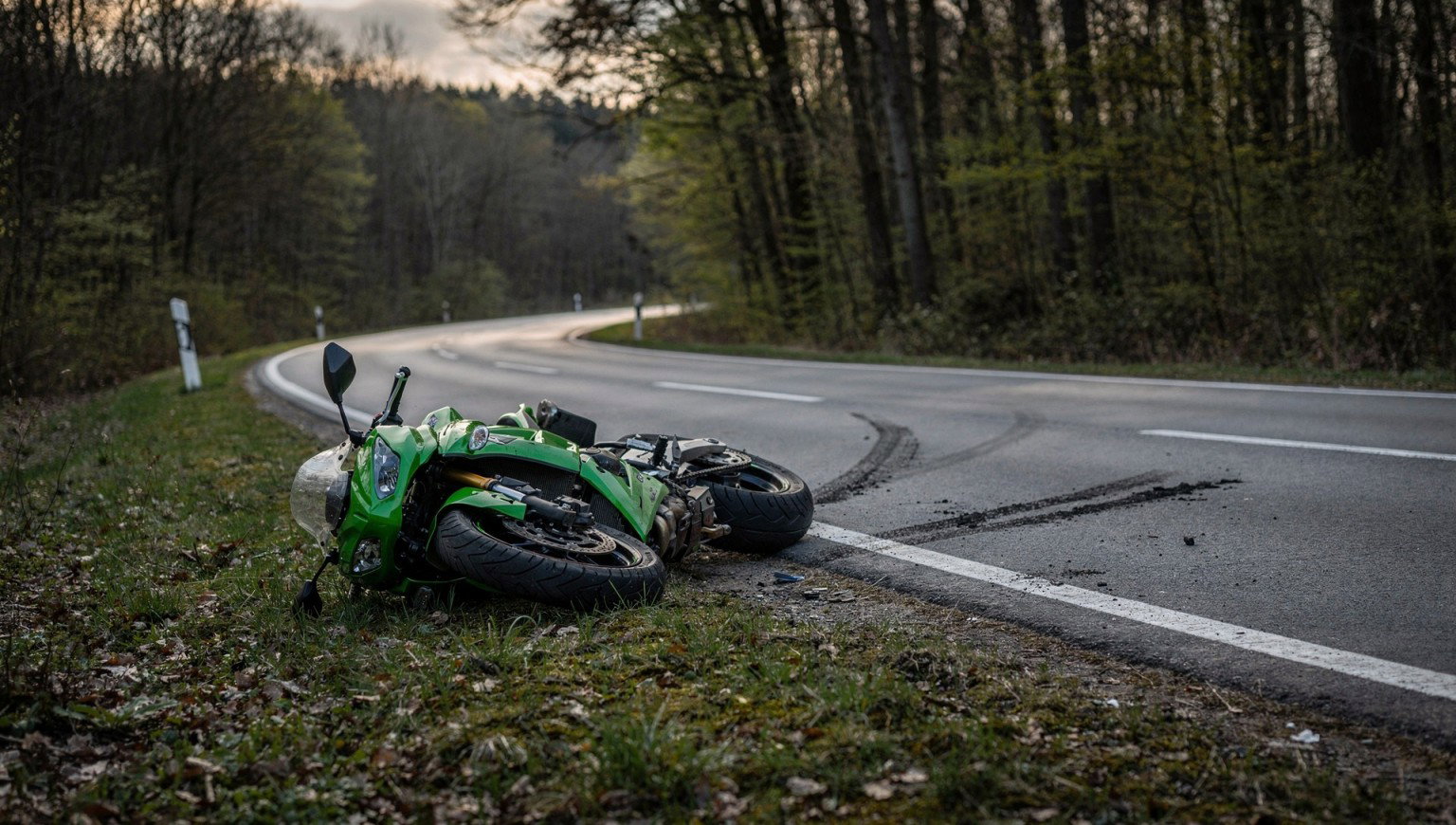 Grüne Kawasaki-Sportmaschine liegt nach Sturz am Rand einer kurvigen Waldstraße, Symbolbild zum Motorradunfall auf der L 3196 bei Steinau an der Straße