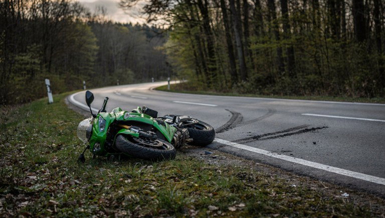 Grüne Kawasaki-Sportmaschine liegt nach Sturz am Rand einer kurvigen Waldstraße, Symbolbild zum Motorradunfall auf der L 3196 bei Steinau an der Straße