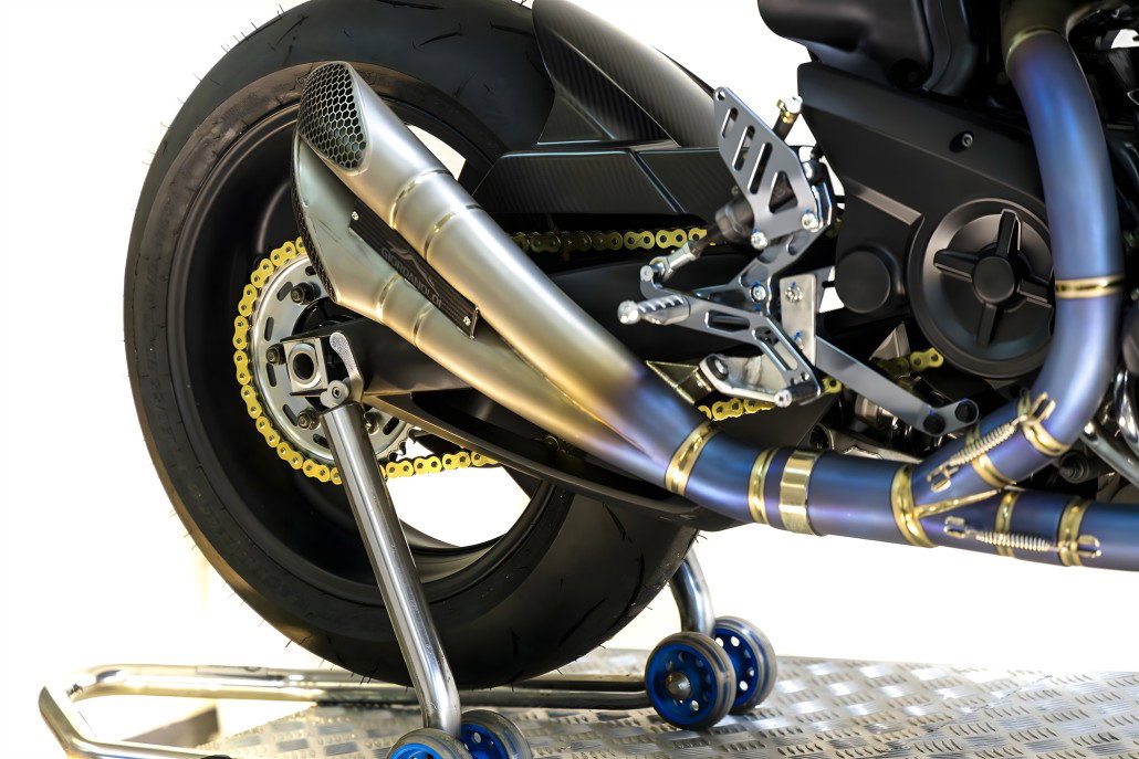 Yamaha MT-01 ORCO – rear wheel and exhaust detail with titanium twin silencer, gold chain, CNC footpegs and blue paddock stand on metal grid