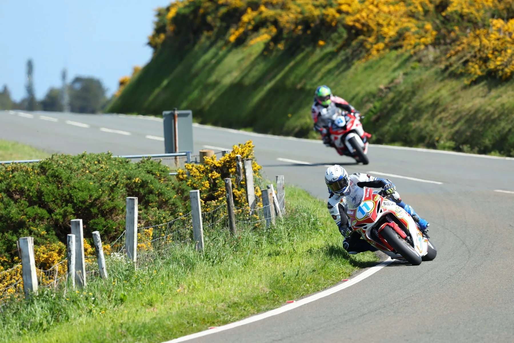 Manx Grand Prix 2026: Zwei Fahrer sterben binnen 24 Stunden 7 Zwei Fahrer in Schraglage auf der Bergstrasse mit Ginsterbuescheln im Hintergrund – Isle of Man TT 2026 Free Practice