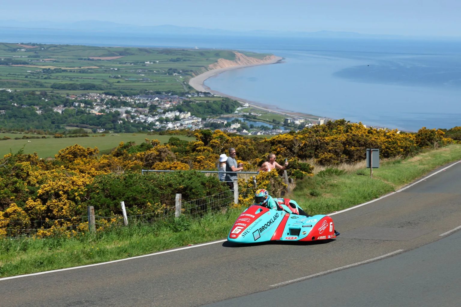 Seitenwagen-Gespann in tuerkiser Lackierung auf dem Mountain Course mit Panoramablick auf die Kueste der Isle of Man – TT 2026 Free Practice