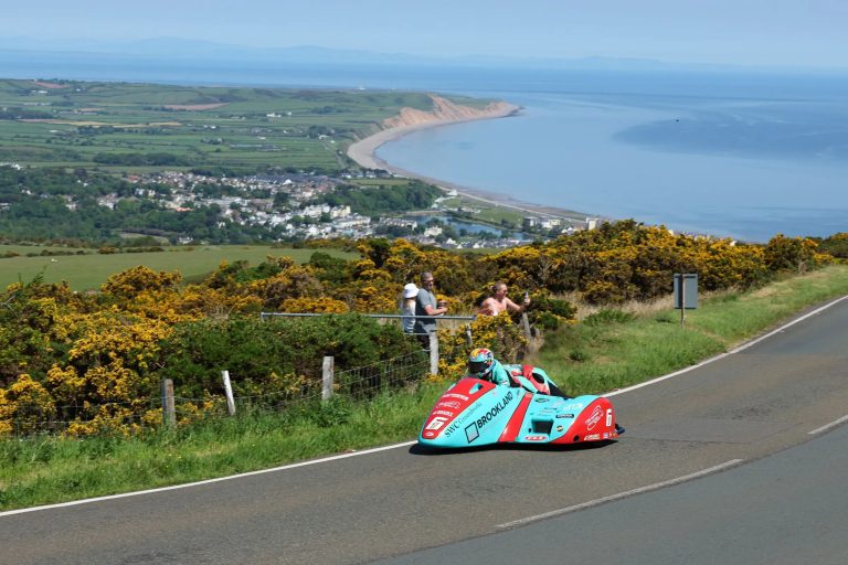 Seitenwagen-Gespann in tuerkiser Lackierung auf dem Mountain Course mit Panoramablick auf die Kueste der Isle of Man – TT 2026 Free Practice