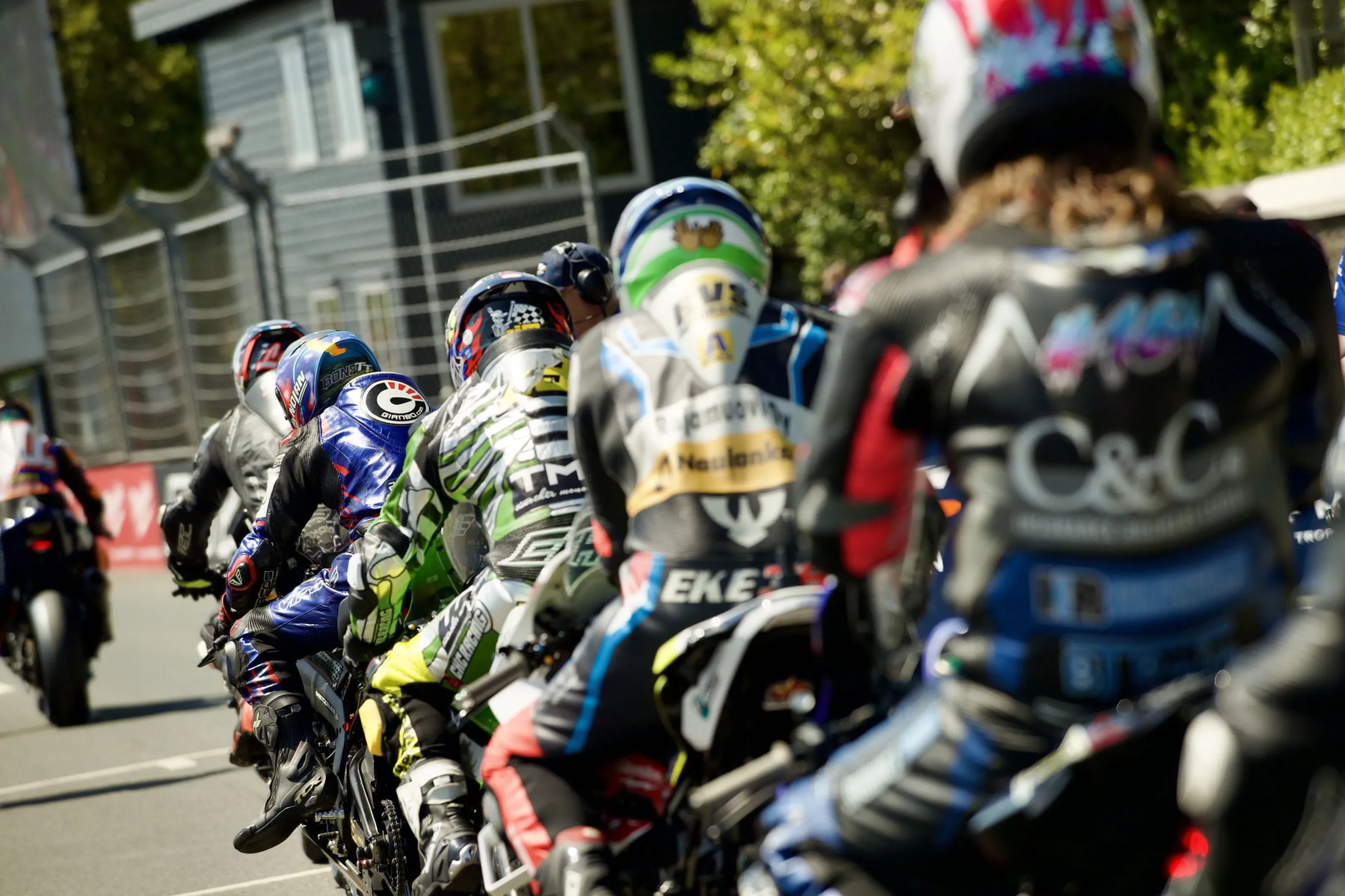 Fahrer in der Startaufstellung von hinten mit bunten Lederkombis und Helmen vor dem Start – Isle of Man TT 2026 Free Practice