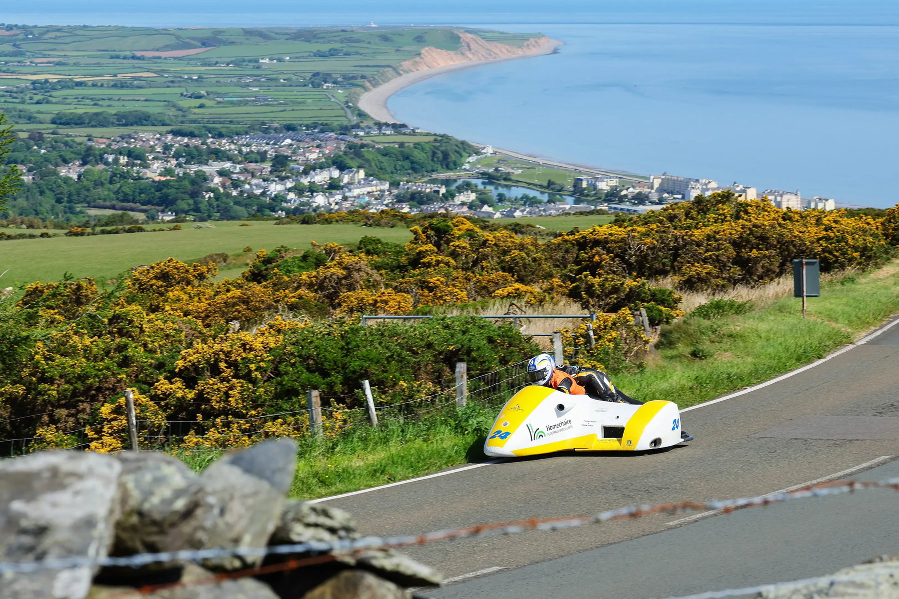 Sidecar-Gespann auf dem Mountain Course mit Panoramablick über die Küste der Isle of Man – Newcomers Speed Controlled Lap TT 2026 Ginsterbüsche und Meer