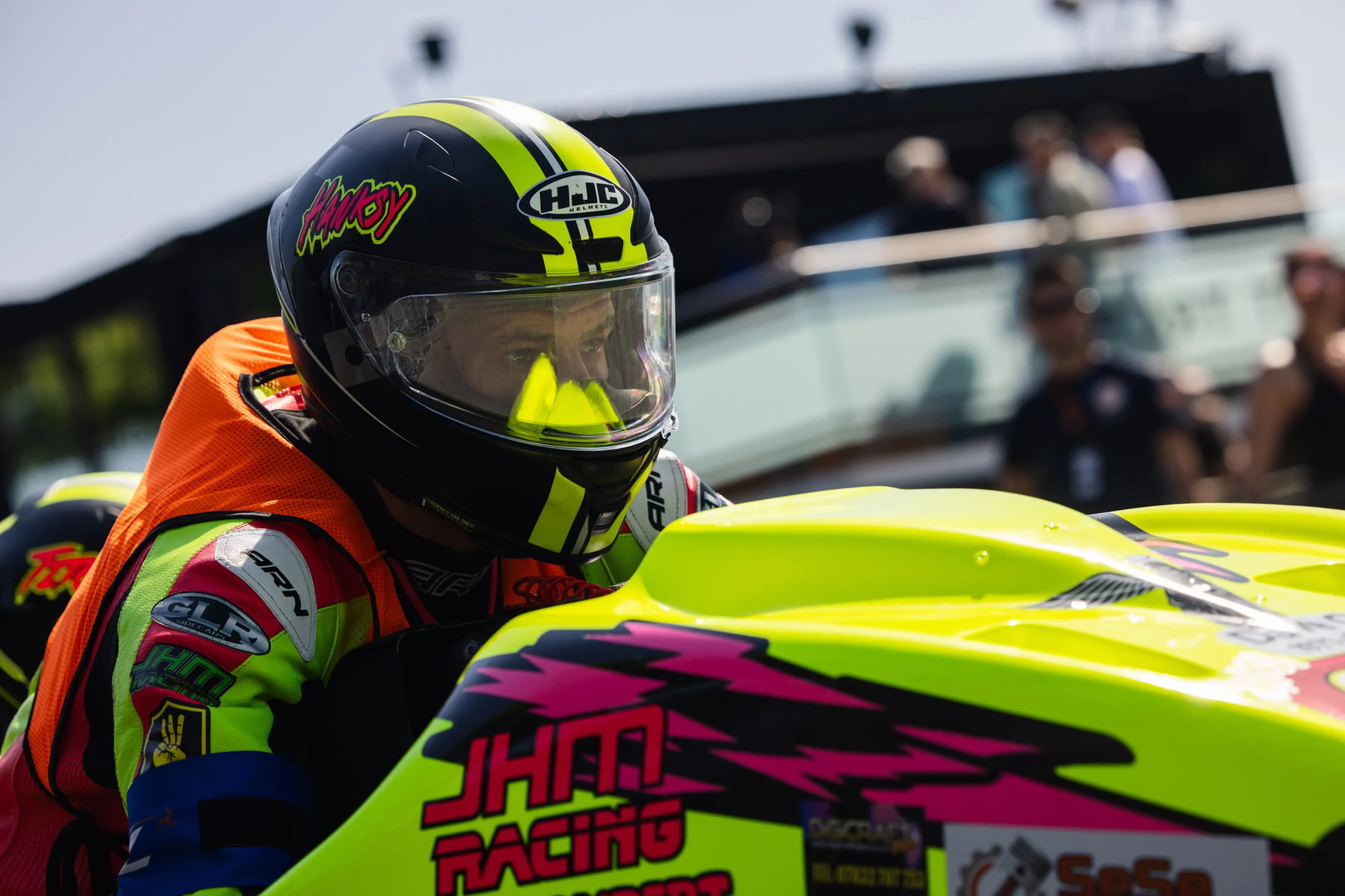 Nahaufnahme Sidecar-Fahrer JHM Racing mit neongelb-pinkem Gespann und HJC-Helm