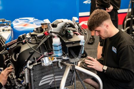 Junger Mechaniker bei Wartungsarbeiten am Kuehler eines Superbikes im Teamzelt – Isle of Man TT 2026 Paddock