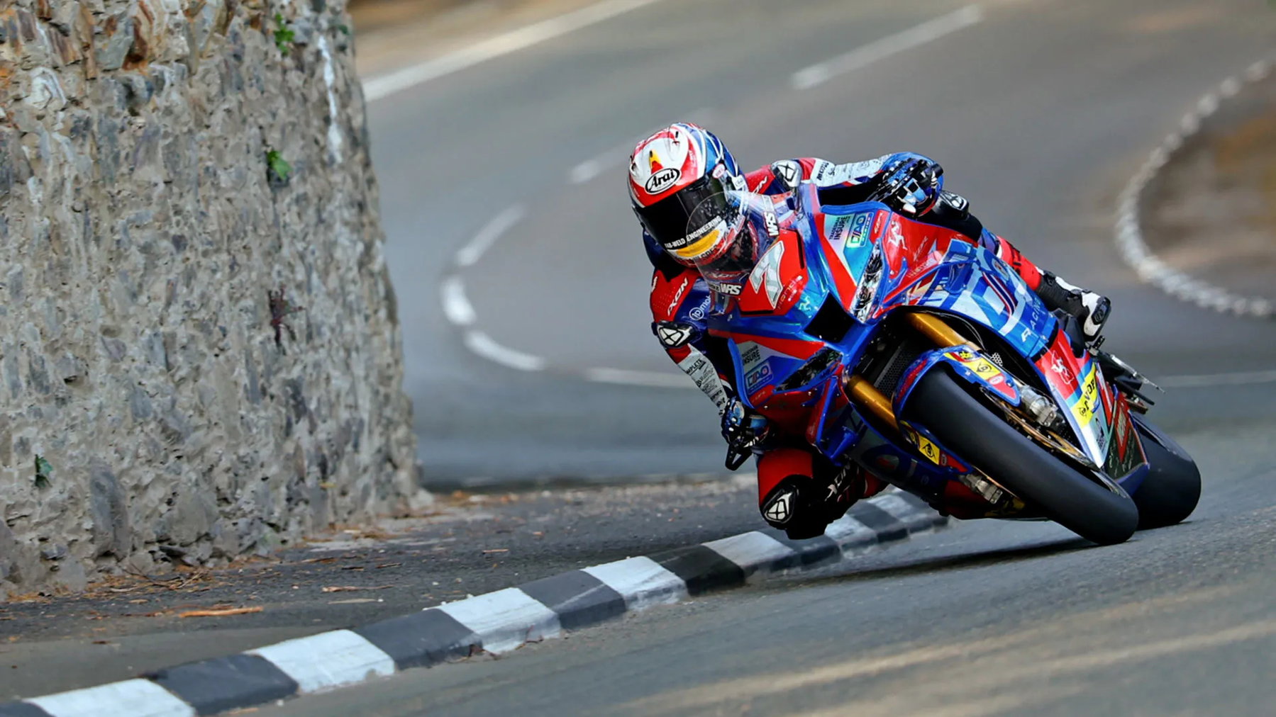 Isle of Man TT: Harrison Dominates, Superstock Podium Wide Open 4 Josh Brookes auf der DAO Racing Honda in Schräglage an Steinmauer – Isle of Man TT 2026 Qualifying Superstock