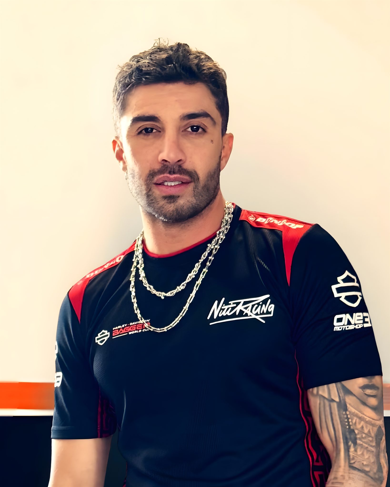 Andrea Iannone Porträt im Nitiracing-Teamshirt mit Harley-Davidson Bagger World Cup Branding, silberne Ketten, Tattoo am linken Arm