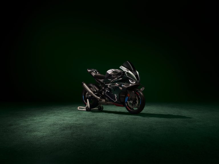 BMW M 1000 RR Limited Edition Isle of Man TT 2026 – Frontansicht schräg rechts in British Racing Green Uni Matt mit TT-Mountain-Course-Grafiken auf der Verkleidung, dunkles Studio mit grünem Spotlight