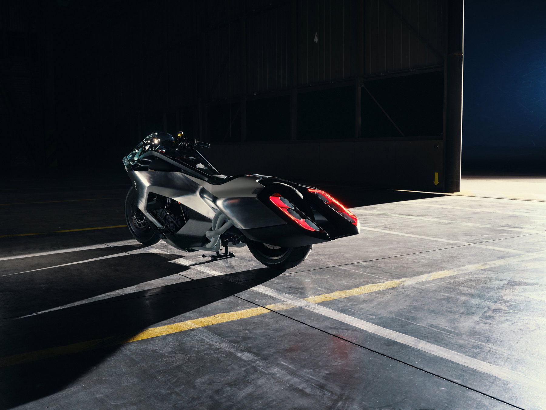 BMW Motorrad Vision K18 – rear view in the hangar with wide carbon tail, six exhaust pipes and red LED lighting
