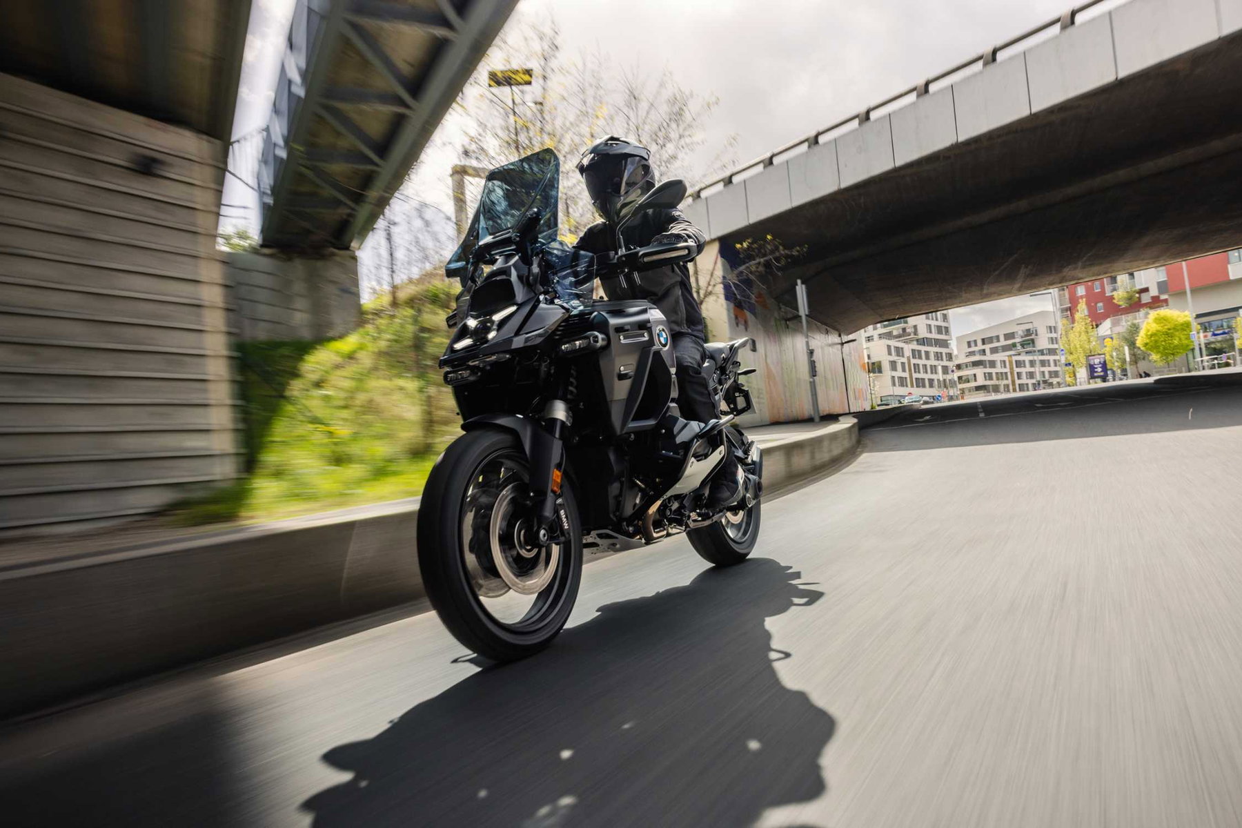 BMW R 1300 GS Adventure Dark Edition 2026 – Dreiviertelansicht von vorne in Fahrt, komplett schwarze Lackierung mit getöntem Windschild