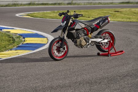 Ducati Hypermotard 698 Mono Nera 2027 – Seitenansicht links auf rotem Montageständer in Kurvenbereich einer Rennstrecke mit blau-gelben Curbs