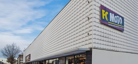 FC-Moto Filiale Würselen Außenansicht – Großes Geschäftsgebäude mit weißer Fassade und buntem FC-Moto-Logo, Aufschrift Motorradbekleidung und Zubehör