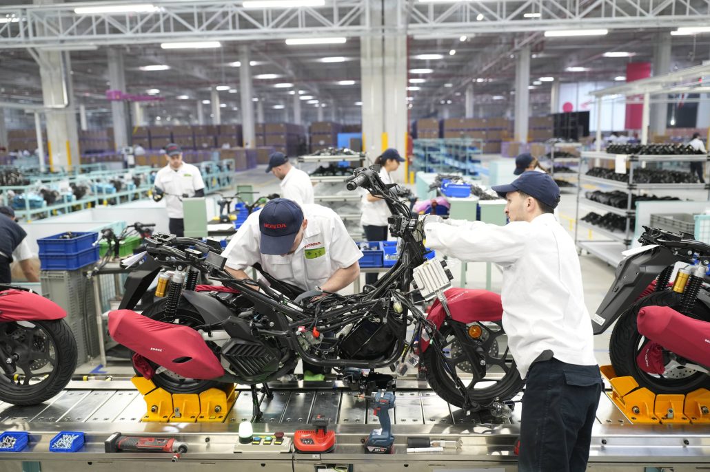 Honda Motorradwerk Türkei 2026 – Arbeiter in weißen Honda-Uniformen bei der Endmontage von Rollern am Fließband im Werk Aliağa