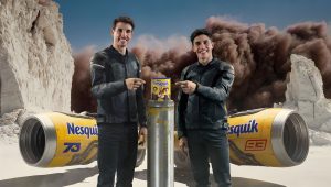 Marc Marquez (93) und Alex Marquez (73) in schwarzen Lederkombis zeigen auf limitierte Nesquik-Dose, im Hintergrund gelbe Nesquik-Rennmaschinen und Wüstenkulisse mit Staubwolke