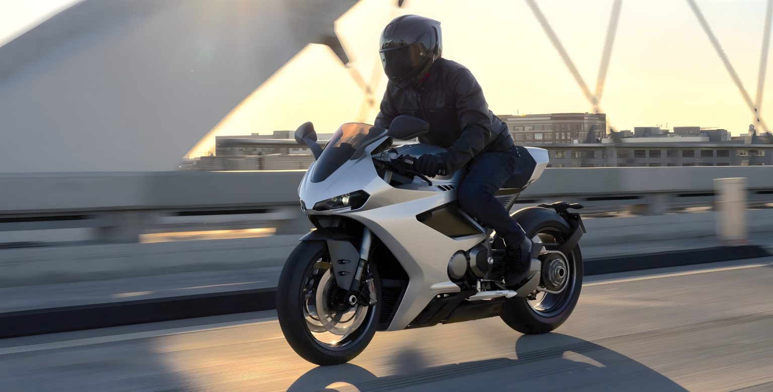Norton Manx R im ersten Praxistest: Was das V4-Superbike auf Straße und Rennstrecke zeigt Norton Manx R Signature 2026 – Fahrer auf silberner Manx R in Schräglage auf Brücke bei Sonnenuntergang, Seitenansicht in Fahrt