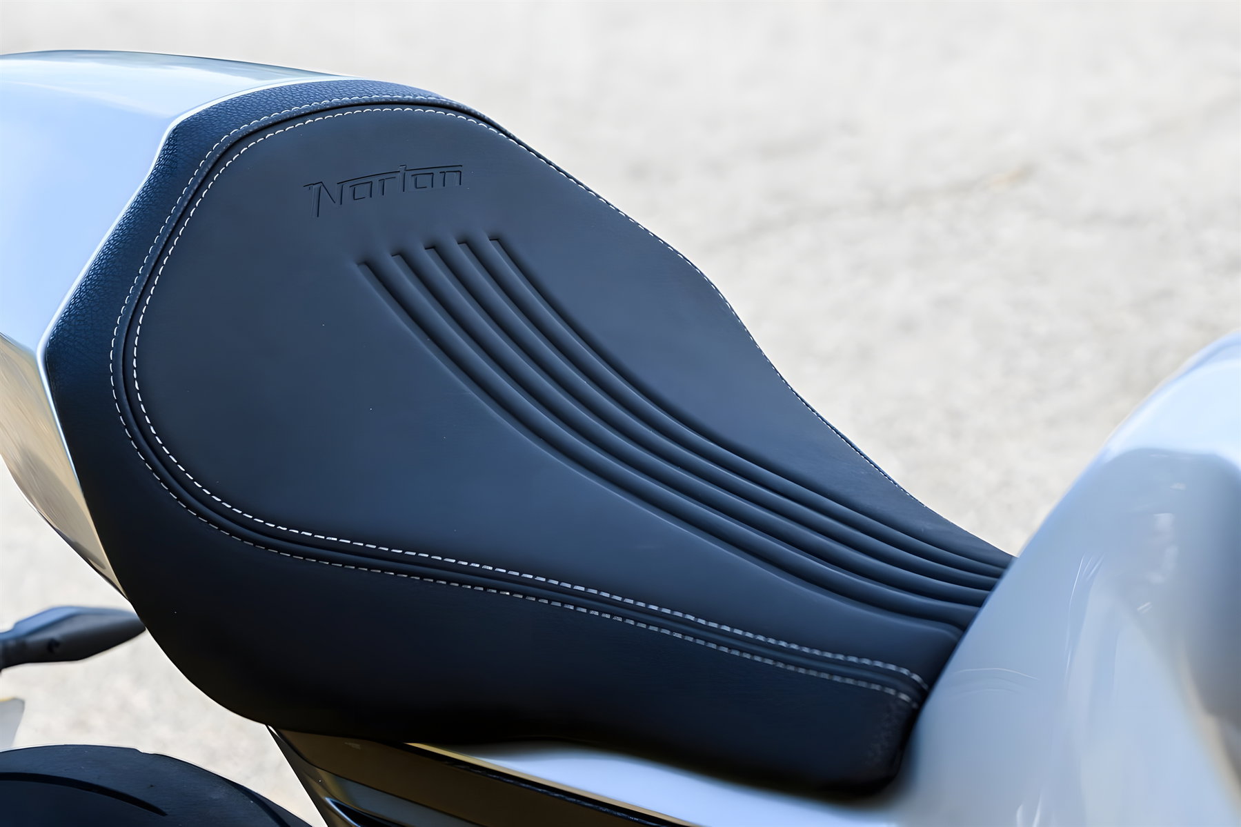 Norton Manx R gewinnt IDEA Award: Was hinter dem Designpreis steckt 3 Norton Manx R Signature 2026 – Detailansicht Einsitzer-Sitzbank mit geprägtem Norton-Schriftzug und Kontrastnaht