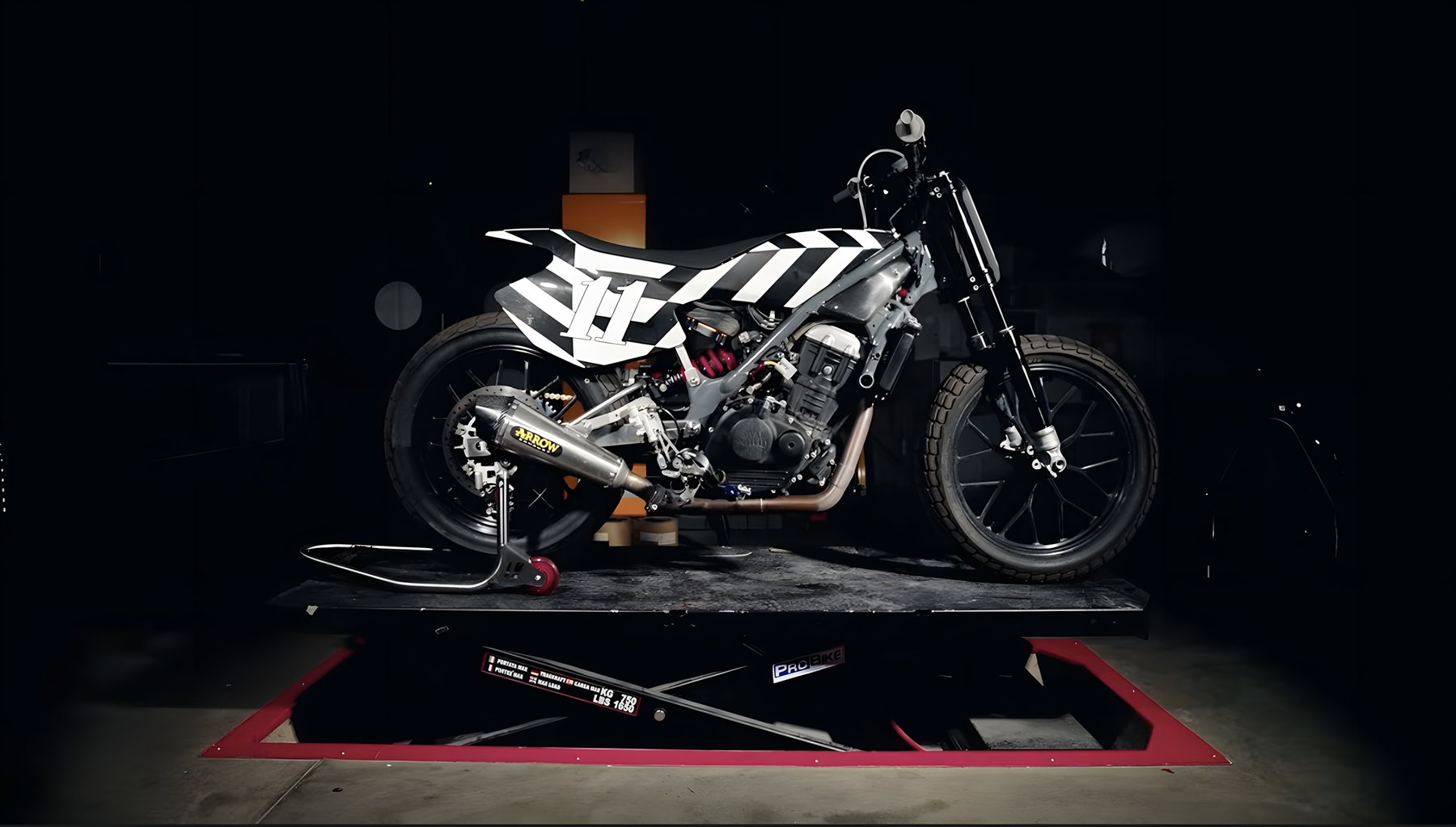 Royal Enfield Sherpa FT Mk2: Erster WM-Einsatz im Flat Track und was das für die Serienversion bedeutet 2 Royal Enfield Sherpa FT Mk2 – Flat-Track-Rennmaschine mit Arrow-Auspuff und schwarz-weißem Chevron-Design auf Werkstatt-Hebebühne