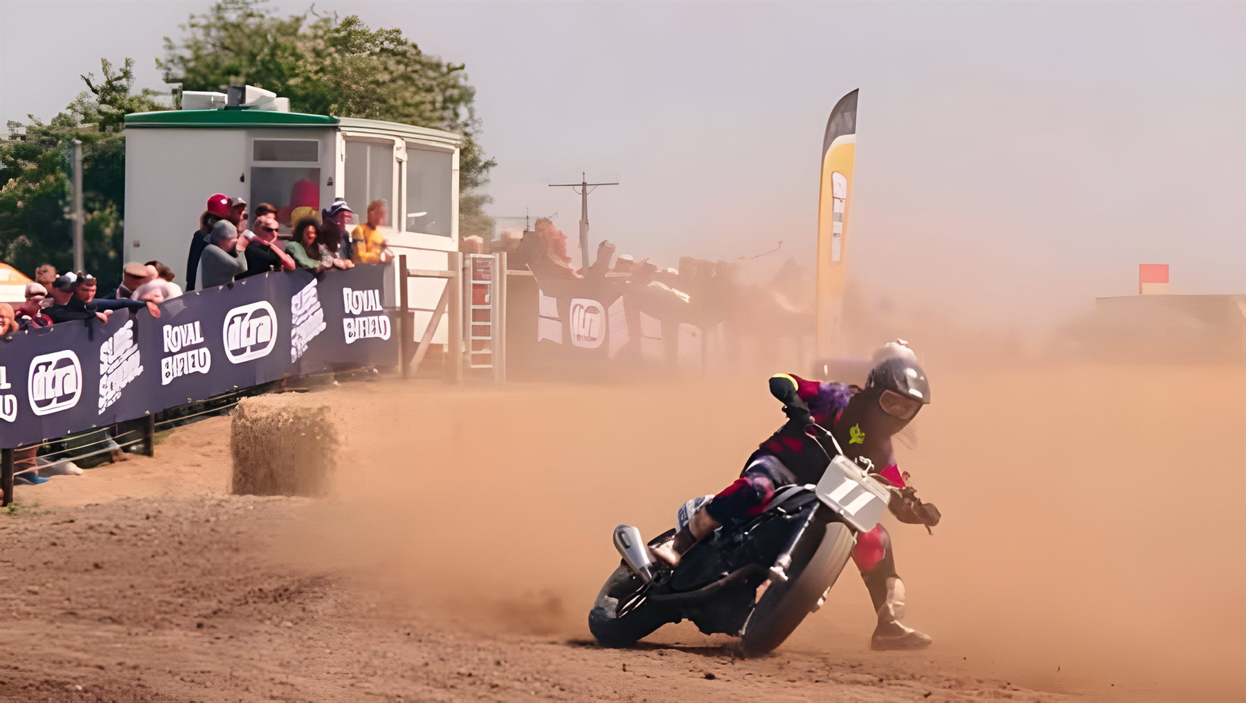 Royal Enfield Sherpa FT Mk2: Erster WM-Einsatz im Flat Track und was das für die Serienversion bedeutet 1 Royal Enfield Sherpa FT Mk2 – Flat-Track-Rennaction mit Fahrer in Schräglage auf Dirtoval, Staubwolke und Zuschauer hinter Royal-Enfield-Bannern
