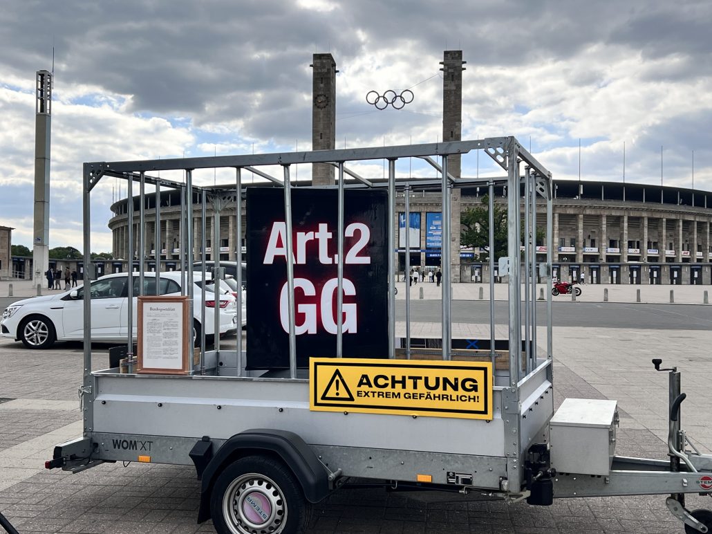 Steel & Speed 2026 – Demonstration trailer with inscription Art. 2 GG in a barred cage and warning sign reading Caution Extremely Dangerous in front of Berlin Olympic Stadium