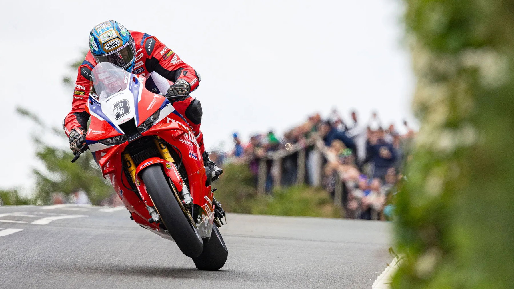 Dean Harrison on the red Honda Racing UK Fireblade number 3 cresting a hill on the Mountain Course, spectators at the roadside - Senior TT preview, Isle of Man TT 2026