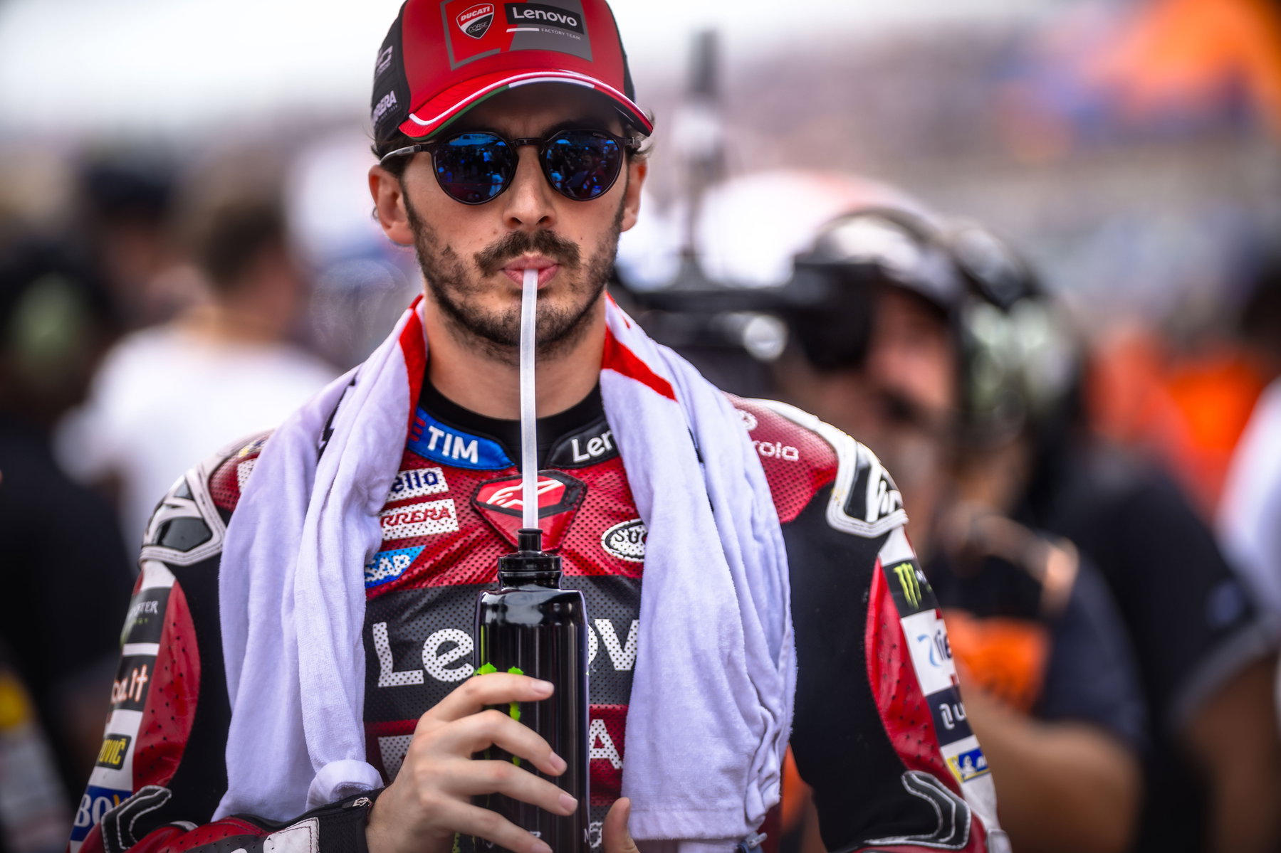 Francesco Bagnaia mit Sonnenbrille und Ducati-Lenovo-Cap trinkt in der Startaufstellung aus seiner Trinkflasche – MotoGP Dutch GP Assen 2026