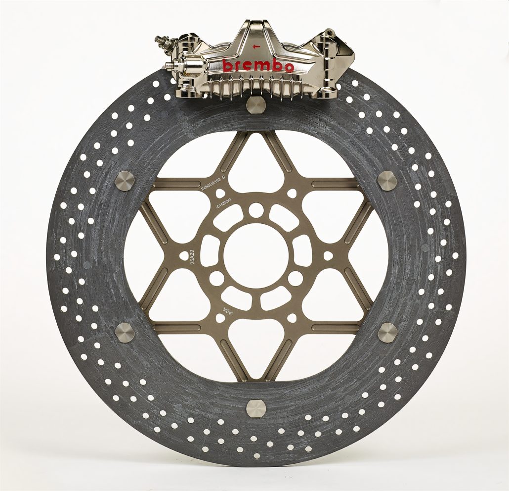 Brembo Hyction: Carbon-Keramik-Bremsen für die WSBK 6 Brembo Hyction Carbon-Keramik-Bremsscheibe und Bremszange Studioaufnahme mit dunkelgrauer Karbonkeramik-Oberfläche goldenem Sternträger und rotem Brembo-Logo