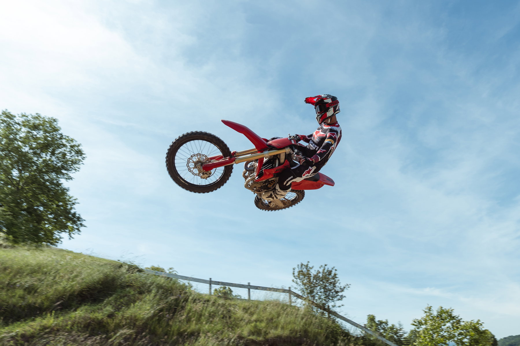 Ducati Desmo250 MX kommt: Desmodromik erobert die 250er-Klasse 8 Ducati Desmo250 MX 2027 – Fahrer springt mit angezogener Maschine über einen Motocross-Hügel vor blauem Himmel, Untersicht auf Showa-Gabel und Vorderrad