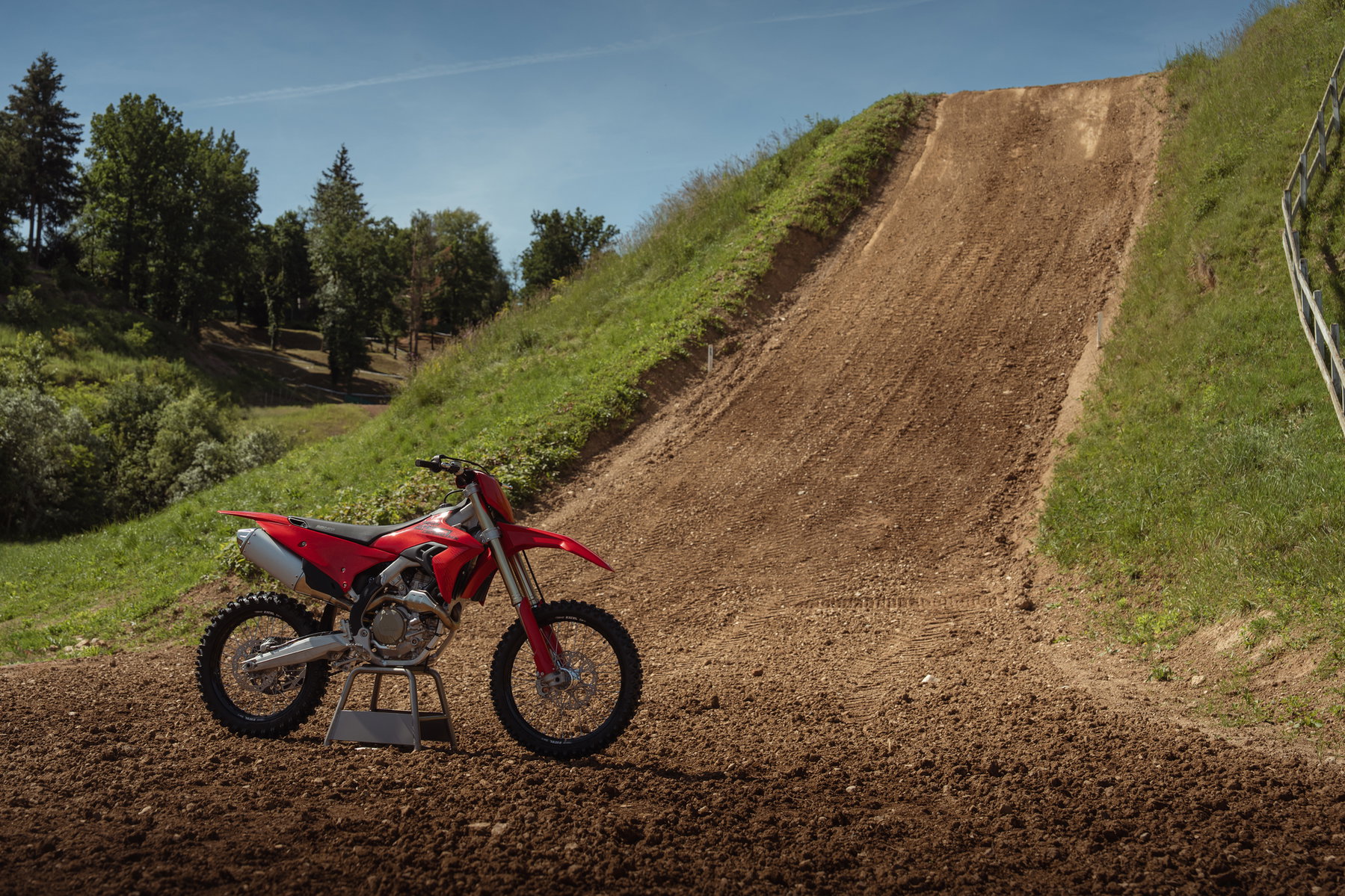 Ducati Desmo250 MX kommt: Desmodromik erobert die 250er-Klasse 1 Ducati Desmo250 MX 2027 in Ducati Red – auf dem Seitenständer vor einer steilen Uphill-Passage einer Motocross-Strecke, Seitenansicht von links