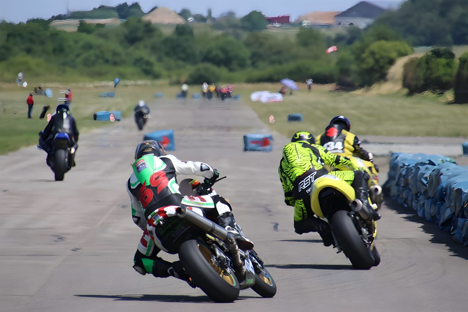 Flugplatzrennen Walldürn: Das letzte seiner Art kehrt im Juni zurück Flugplatzrennen Walldürn 2026 – Zwei Superbike-Fahrer im Zweikampf auf der Flugplatz-Geraden, Startnummern 6 und 34 in Schräglage vor Reifenstapel-Begrenzung bei Sonnenschein