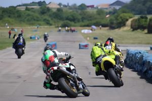 Flugplatzrennen Walldürn 2026 – Zwei Superbike-Fahrer im Zweikampf auf der Flugplatz-Geraden, Startnummern 6 und 34 in Schräglage vor Reifenstapel-Begrenzung bei Sonnenschein