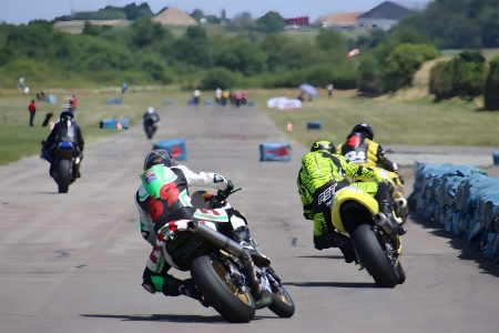 Flugplatzrennen Walldürn 2026 – Zwei Superbike-Fahrer im Zweikampf auf der Flugplatz-Geraden, Startnummern 6 und 34 in Schräglage vor Reifenstapel-Begrenzung bei Sonnenschein