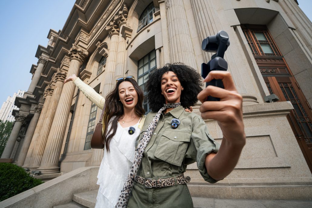 Zwei lachende Frauen machen mit der Insta360 Luna Ultra in Nacht Schwarz eine Selbstaufnahme vor einem Gebäude mit Säulen