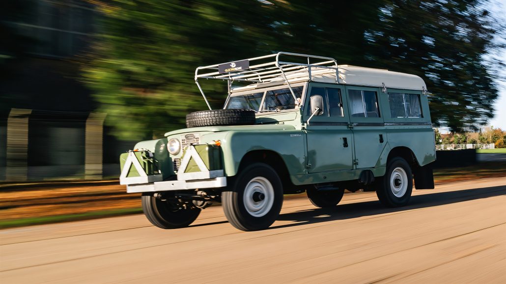 Jason Momoas 1920er-Harley wird zum Plug-in-Hybrid: Technik im Detail 5 Land Rover Series IIA Dormobile EV-Conversion fahrend – mintgrün-weiß mit Dachgepäckträger und Ersatzrad, dynamischer Schwenk auf Landstraße