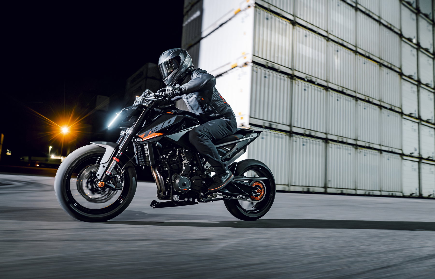 KTM 790 Duke 2027 in Action – Fahrer beschleunigt vor Containerstapeln bei Nacht