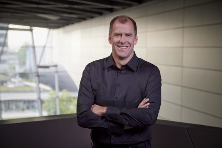 Christof Lischka, künftiger KTM CTPO – Porträt im schwarzen Hemd mit verschränkten Armen in modernem Gebäude, lächelnd in die Kamera blickend